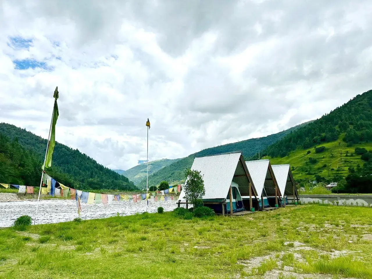 Camping tents with colorful prayer flags by the river in Sangti Valley
